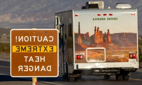 An RV drives past a sign that reads "Caution! Extreme heat danger."